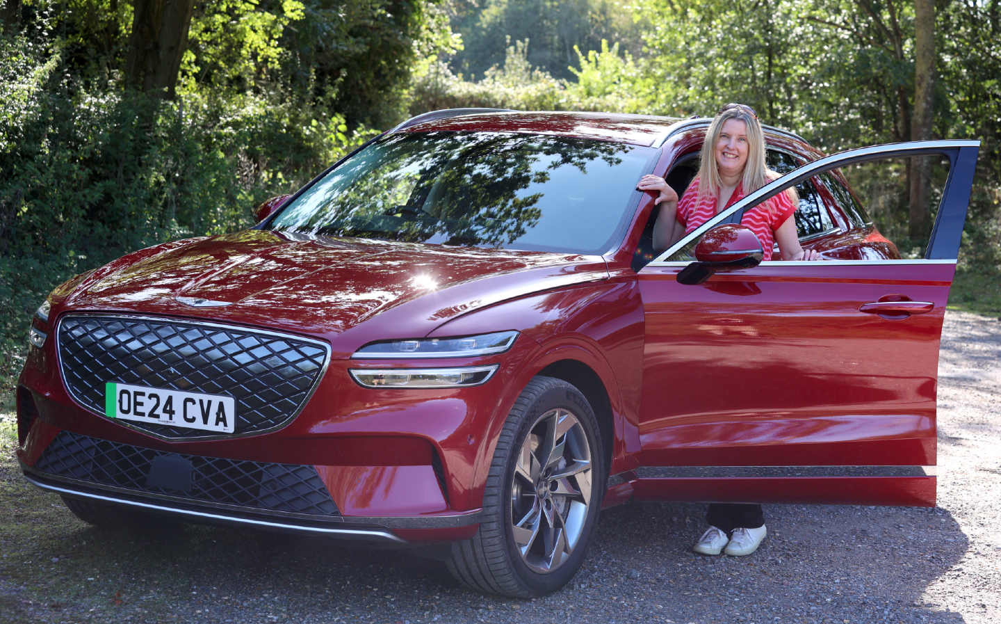 Tina Milton stands by a red Genesis Electrified GV70 for her long term review